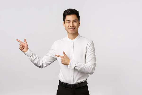 Joven asiático hombre de negocios en un traje señalando con su dedo en el fondo blanco . — Foto de Stock