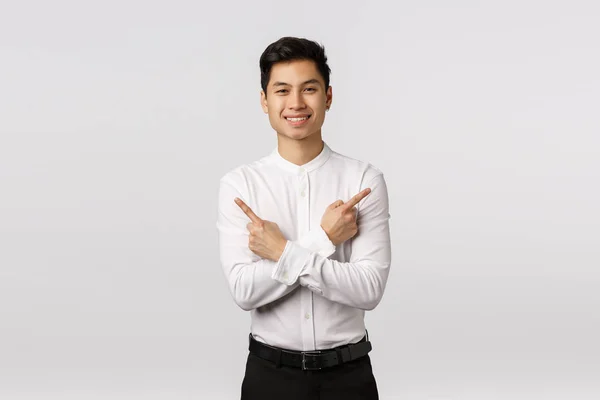 Přátelsky vypadající atraktivní úspěšný asijský podnikatel dát radu, kde najít vše potřebné, ukazuje do strany, aby kříž přes tělo a bod vlevo a vpravo, bílé pozadí — Stock fotografie