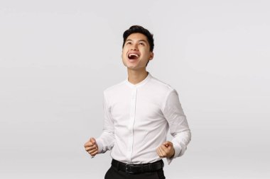 Evet bebeğim, Tanrı 'ya şükür kazandım. Adam başarılı bir anlaşmayı kutluyor. Memnun, neşeli Asyalı genç adam yumruk tokuşturur, evet de ve rahatla, hedefe ulaş, kazan, beyaz arka plan