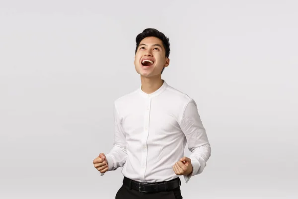 Sí, gracias a Dios que gané. Hombre celebrando un trato exitoso. Agradable, alegre atractivo joven asiático chico puño bomba, decir sí en el cielo y sonriendo aliviado, lograr objetivo, ganar, fondo blanco — Foto de Stock