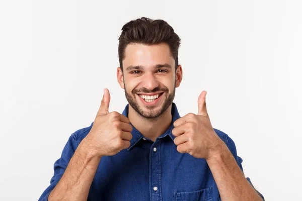 Gelukkig casual jonge man duim opdagen en glimlachend geïsoleerd op witte achtergrond. — Stockfoto