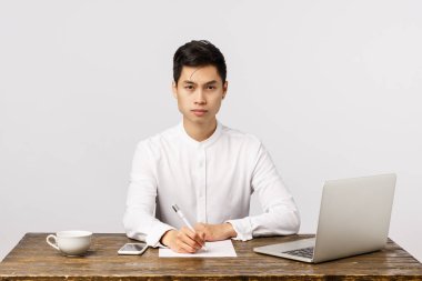 Kararlı ve iddialı, ofiste çalışkan genç Asyalı işadamı, masa başında oturmuş kağıtlar yazıyor, kameraya kendinden emin bakıyor, kendi şirketini yönetiyor, dizüstü bilgisayarında posta bekliyor, beyaz kahve içiyor.