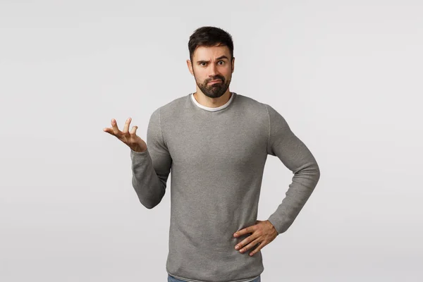 I dont know. Perplexed, indecisive clueless handsome bearded boyfriend in grey sweater, cant figure out what best buy, where shop, raise one hand and shrugging, smirk puzzled, white background — Stock Photo, Image