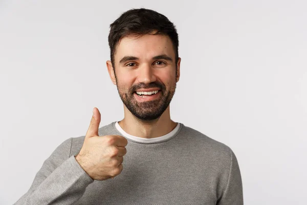 Закрытый снимок надежный и довольный улыбающийся, счастливый мужчина с бородой в сером свитере, показуха одобряет, нравится или рекомендует услугу компании, думает, что все отлично, увядает позитив. — стоковое фото