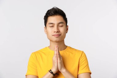 Huzurlu, rahat, sakin, yakışıklı Asyalı adam, stres at ve mutlu meditasyon yap, yoga yap, dua etmek için el ele ver, gözlerini kapat ve gülümse.