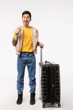 Yolculuk, modern yaşam tarzı ve seyahat konsepti. Neşeli, heyecanlı Asyalı genç adam sonunda dünya turuna çıkmaya hazır bavulunu topladı ve havalimanında yolcu bekliyor.