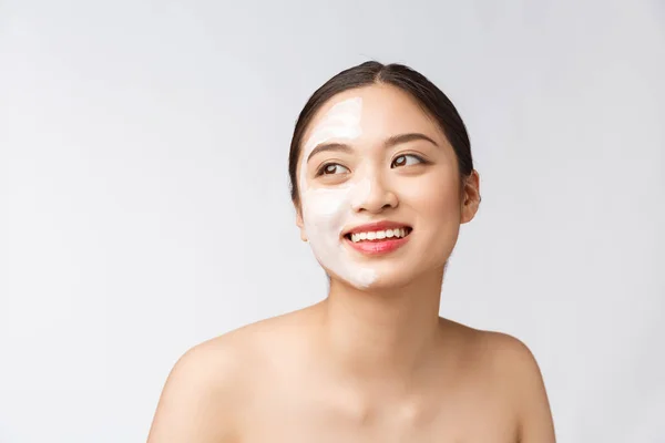 Чарівна приємна жінка наносить крем на половину обличчя — стокове фото