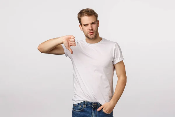 Serious-looking, skeptical and judgemental handsome blond bearded guy show thumb-down and looking disappointed, give negative feedback, upset with poor results, judging, white background — Stock Photo, Image