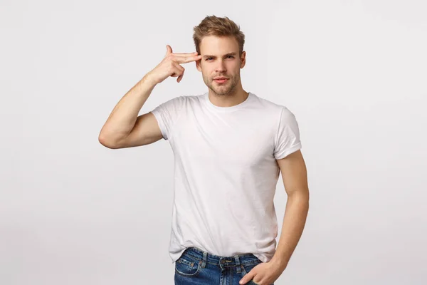 Pense antes de agir. Sassy inteligente bonito bonito jovem loiro em branco t-shirt tocando templo, apontando para a cabeça ou cérebro e sorrindo auto-confiante, dizendo tomada de decisão sábia — Fotografia de Stock