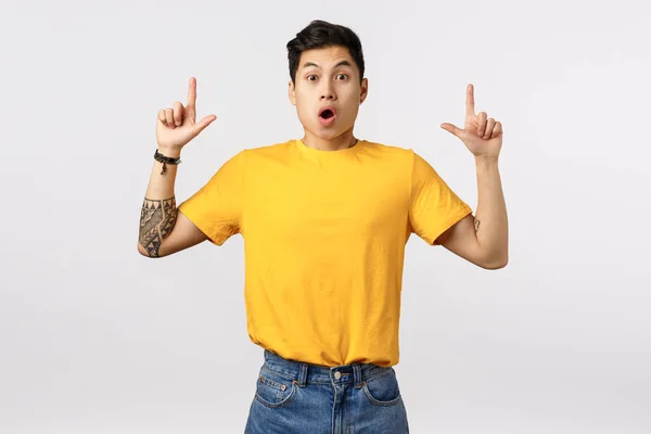 Wow incredible, check this out. Astonished and amused speechless shocked asian handsome young man in yellow t-shirt, open mouth in wonder and amazement, gasping impressed, white background — ストック写真