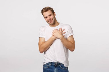 Minnettar ve duygulu, sevimli sarışın beyaz adam şükranlarını sunar ve büyülenir, el ele tutuşur pohpohlanır, gülümser, güzel hediye için teşekkür eder, mutlu beyaz arka planda durur.