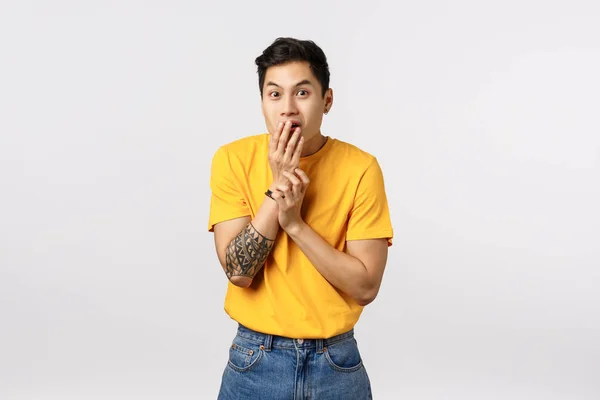 Wow no way, tell me more. Intrigued and excited handsome smiling asian guy with tattoos, cover mouth with palm, giggle and gasping surprised, gossiping, heard fresh rumor, white background — Stock Photo, Image