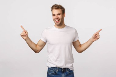 Yakışıklı, yakışıklı, sarışın, beyaz erkek, kaygısız gülüyor ve mutlu, büyük fırsatlara sahip, iki yol ya da seçenekler, yanlamasına işaret ediyor, tavsiye ver, sol ve sağ ürün tanıtımını göster