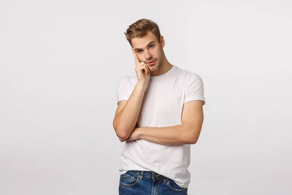 Molesto y harto joven rubio cansado escuchando charla aburrida poco interesante, mirando hacia otro lado distante con expresión pensativa, confusa, inclinarse en la mano, pensando, espacio fuera, fondo blanco —  Fotos de Stock