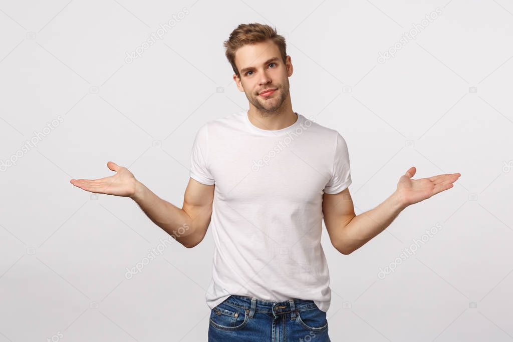 Sorry, I dont know. Careless and tired, unbothered blond young guy, spread hands sideways and shrugging, tilt head as apologizing for failing, making mistake, standing white background