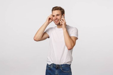 Hevesli ve meraklı, kaygısız gülümseyen sarışın beyaz adam ilginç bir konuşma yaptı, çalışandan telefon aldı, iyi haberler aldı, akıllı telefonu kulağına yaklaştırdı, telefonla konuştu, kulaklarına dokundu.
