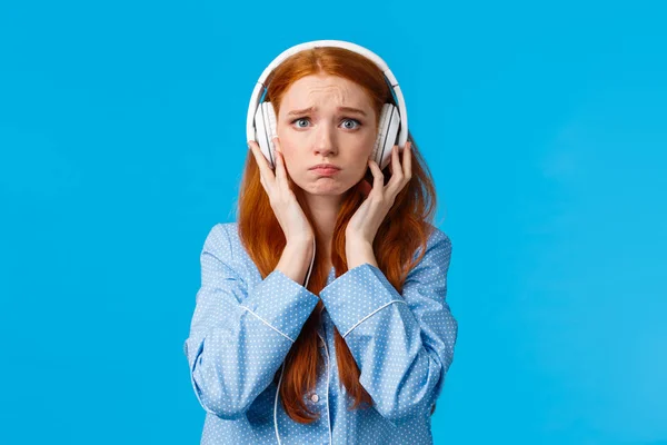 Menina sobre chorar de canção emocional. Namorada ruiva perturbada sofrendo rompimento, chorando ouvir música em grandes fones de ouvido brancos, de pé fundo azul em roupas noturnas, infeliz — Fotografia de Stock