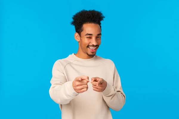 You rock, congratulations. Sassy good-looking african american hipster guy pointing fingers at camera and winking as choosing, indicating at winner or lucky person who achieved goal, blue background — Stock Photo, Image