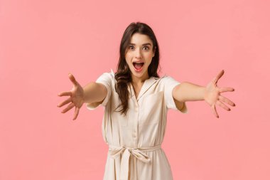 Kollarıma gel. Heyecanlı beyaz kız elini uzatıyor, bir şeyler tutuyor, neşeyle gülümsüyor, sarılıyor, kız arkadaşını selamlıyor, alışverişe gidiyor, pembe arka plan.