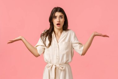 Yanlış olan ne? Kafası karışmış ve gergin, beyaz elbiseli, omuz silkmiş esmer kız ne olduğunu anlamıyor, ellerini yana doğru kaldırıyor ve cahil bakıyor, cevap veremiyor, pembe arka plan