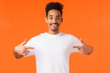 Optimistic happy and cute african-american hipster guy, want make a change, volunteer, willing participate, pointing himself telling he is one, perfect candidate, standing orange background clipart