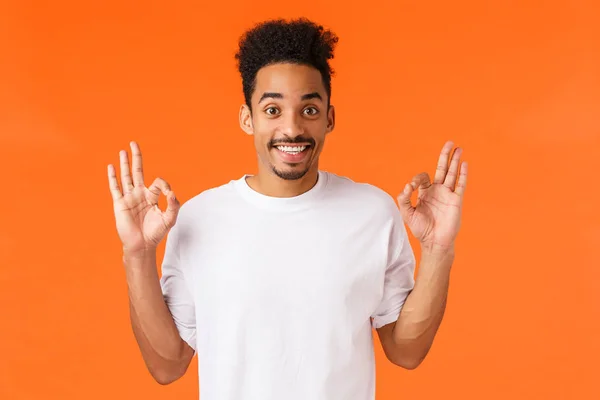 Guy ging zufrieden mit seiner Leistung. Glücklich entzückt afrikanisch-amerikanischer Mann in weißem T-Shirt zeigt okay Geste, stimme mit Ihnen überein, lächelnd Annahme Plan, nicken Zustimmung, empfehlen Produkt, sagen in Ordnung — Stockfoto