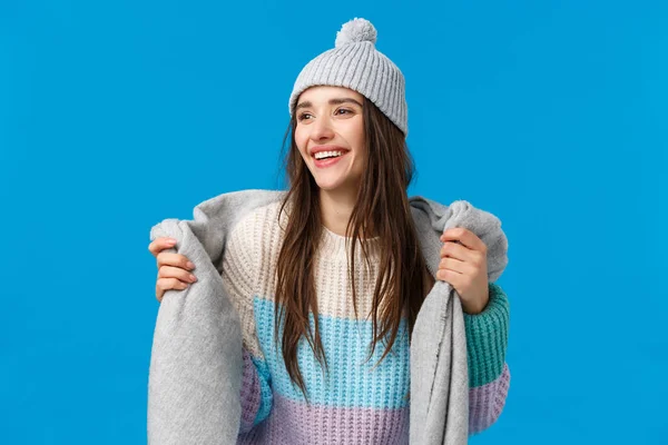 Attractive and carefree, dreamy pretty woman with long dark hair, wearing winter hat, sweater, wrapping scarf around neck going outside, ski and enjoying christmas holidays, look away smiling — Stock Photo, Image