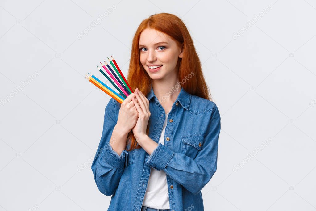 Waist-up portrait dreamy and talented good-looking redhead female student create design project, draw architecture, holding colored pencils and smiling camera happy, white background