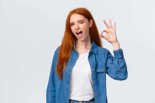 Waist-up portrait cheeky, confident and relaxed, chill redhead woman saying all alright, encourage everything okay, showing ok gesture wink and tongue, standing white background — Stock Photo, Image