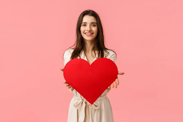 Here my love to you. Charming tender and alluring, romantic young woman giving big heart card to camera, smiling delighted, express her affection and admiration, standing pink background — Stock Photo, Image