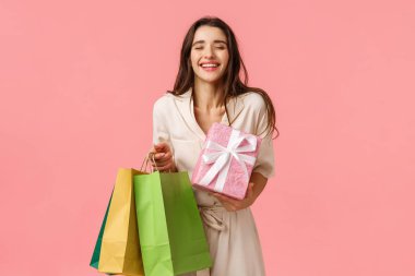 Kaygısız, keyifli kadın alışverişkolik, kız bir sürü hediye aldı, elinde alışveriş çantası ve güzel bir hediye, kapalı gözler ve gülümseyen rüya gibi doğum günü partisi, pembe arka plan