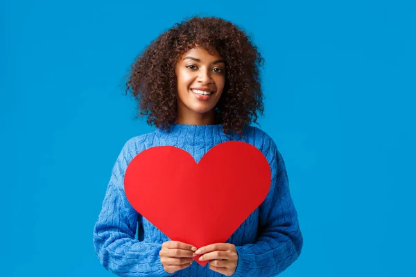 Be my valentine. Romantic and sensual cute african-american woman with afro haircut, holding big red heart sign and smiling, confessing love, searching soulmate, have perfect relationship