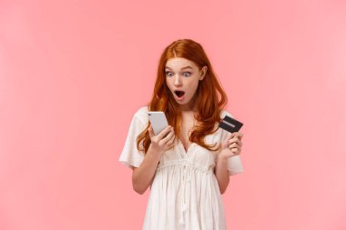Şok olmuş ve korkmuş beyaz saçlı genç bir kız banka hesabında akıllı telefon uygulaması, cep telefonu ve kredi kartı ile sallanan bir şey gördü. Düşük çeneyle görüntüye baktı.