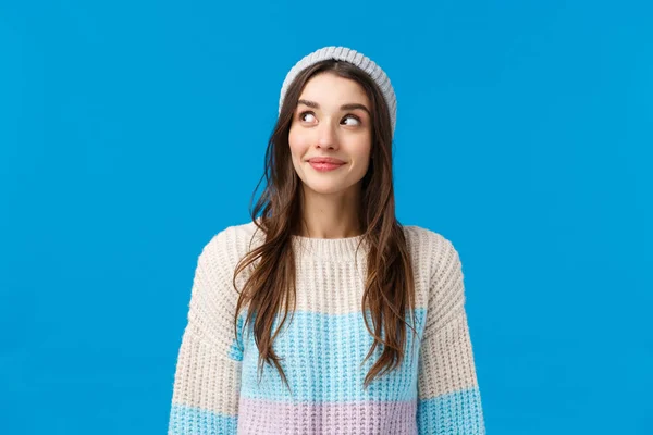 Chica curiosa lo que sucede en la esquina, mirando y sonriendo emocionado, quiere ver algo interesante pasando, de pie fondo azul optimista con una sonrisa encantadora, usar suéter de invierno y sombrero — Foto de Stock