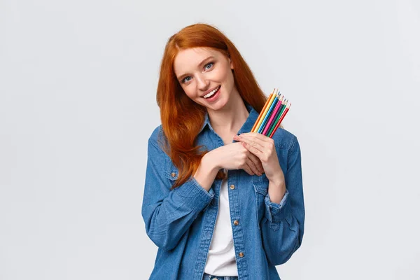 stock image Creativity, imagination and people concept. Cheerful good-looking female college student painting, likes create artworks, holding colored pencils and smiling, tilting head dreamy, white background