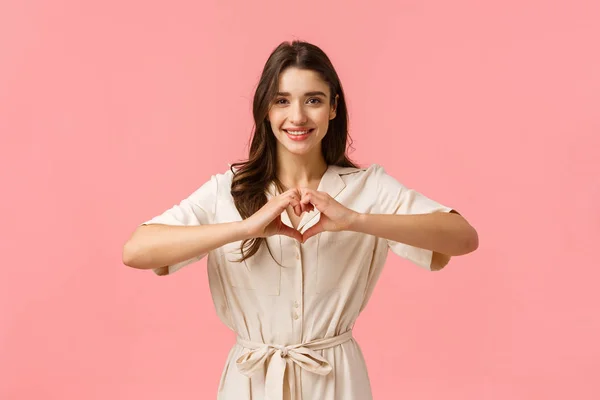 Waist-up portrait charming young brunette girl in dress, showing heart sign with love or care, absolutely adore boyfriend, having perfect relationship, feeling happy, smiling joyfully — 스톡 사진