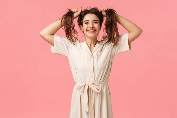 Alegria, festa e conceito de felicidade. Menina engraçada tola se divertindo brincando, puxando o cabelo lateralmente tornando-o bagunçado, sorrindo alegre, desfrutar de dia perfeito sentindo-se divertido e otimista, fundo rosa — Fotografia de Stock