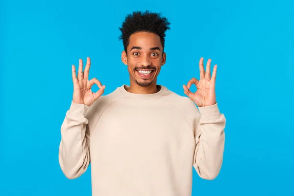 Alright, sounds good. Handsome excited smiling african-american man with afro haircut, moustache showing okay gesture, agree, satisfied with awesome winter secret santa party, blue background — Stock Photo, Image