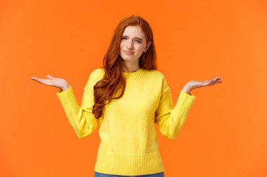 Saçma sapan sorular duyan bir kız. Sarı kazaklı, umursamaz ve rahatsız edilmemiş kızıl saçlı bir kadın ellerini yana kaldırarak omuz silkiyor, kaşlarını çatıyor, kararsız, kafası karışık.