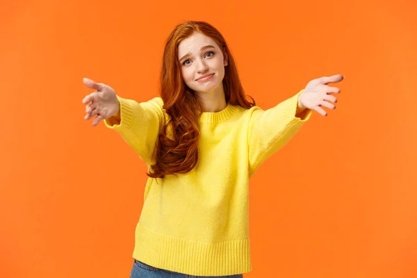 Girl asking come here to give cheer-up hug. Cute and touched tender redhead woman in yellow sweater, extend arms,stretch hands forward for cuddle, embrace friend, smiling lovely, orange background