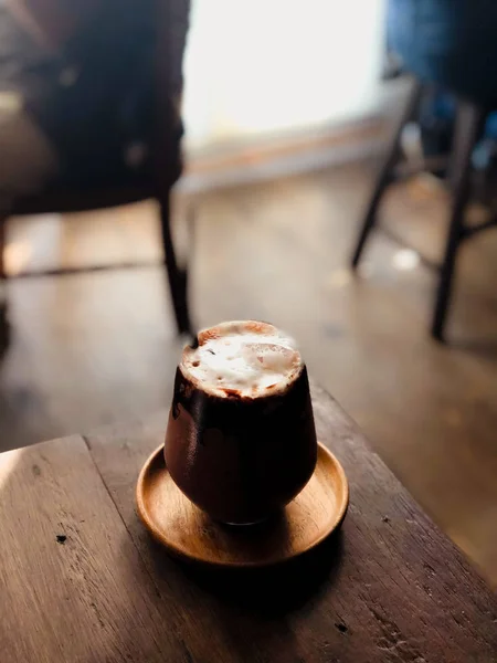 Zbliżyć nowoczesny gorąca czarna czekolada w filiżance patrząc i czuć się tak pyszne na drewnianym stole w kawiarni. — Zdjęcie stockowe