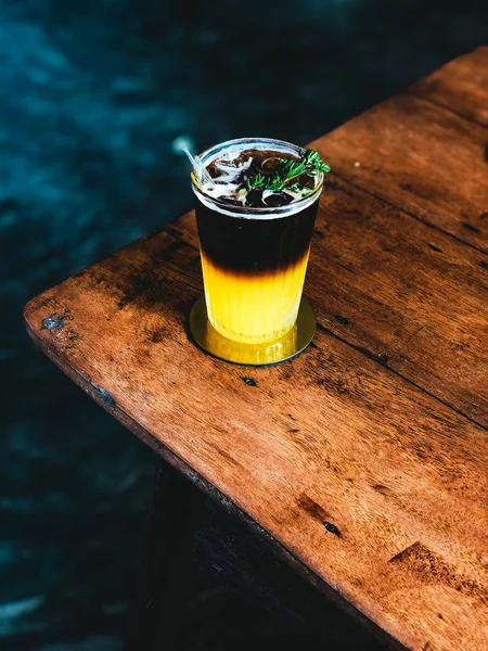 Sumo de laranja fresco gelado coberto com café expresso em mesa de madeira no café moderno . — Fotografia de Stock