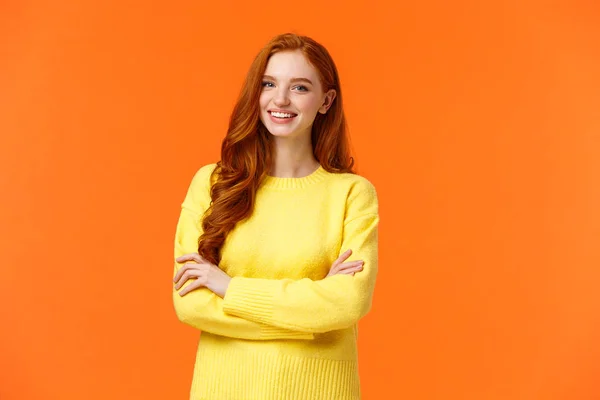 Concepto de negocios, comercio electrónico y personas. Estudiante moderna, chica pelirroja aprender TI, diseño digital en la universidad, brazos cruzados sobre el pecho con confianza, postura asertiva, sonriendo feliz, fondo naranja —  Fotos de Stock