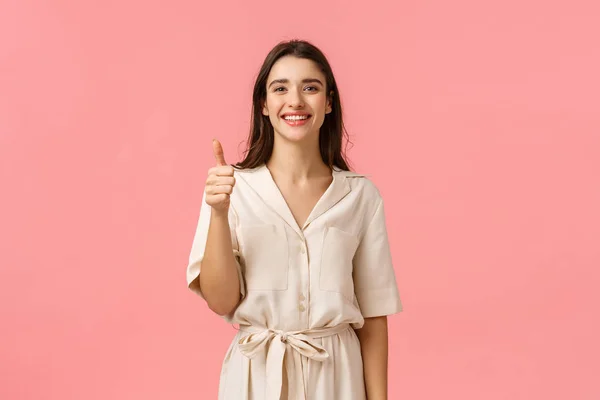 Dar feedback positivo, recomendação. Boa aparência alegre, menina macia em vestido lindo, mostrando polegar-up na aprovação, satisfeito ou gesto publicitário, sorrindo como produto, fundo rosa — Fotografia de Stock