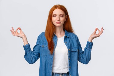 Sabır, zen ve modern yaşam tarzı konsepti. Huzurlu, sakin ve rahatlamış gülümseyen kızıl saçlı kadın meditasyon yapıyor, lotus pozunda el ele tutuşuyor, yoga yapıyor, beyaz arka plan üzerinde çalışıyor.