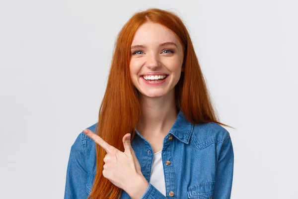 Detailní portrét odcházející dobře vypadající veselá zrzka dospívající dívka v ležérní oblečení, smích a mluvení, diskutovat o nedávné události, ukazující prstem vlevo na banner, doporučit reklamu — Stock fotografie