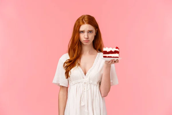 Waist-up portrait upset, uneasy and gloomy cute birthday girl feeling unhappy, sighing, pouting and looking camera distressed, holding peace cake on plate unsatisfied with bad party, pink background — Stock Photo, Image