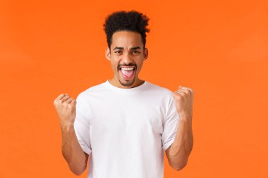 Evet, ben yaptım. Kazanan ve şampiyon, rahatlamış Afro-Amerikan adam kendinden emin hissediyor, kaslarını gevşetiyor, yumruk sallıyor ve evet diyor zafer, başarı veya ödül, kazanma bahsi, turuncu arka plan