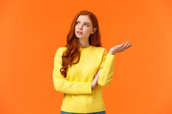 Troubled and unsure, indecisive cute redhead girl trying solve problem, searching resolve, looking perplexed upper left corner pondering, raise hand uncertain, confused, shrugging, orange background — 스톡 사진