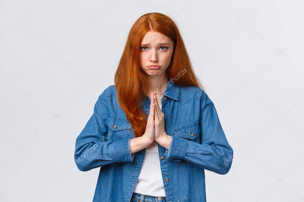 Waist-up portrait gloomy cute redhead girl begging aplogy, press hands together in pray, pouting and looking camera pleading, asking help, sorry, feeling regret for causing mess, white background
